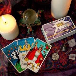 Tarot cards laying on a table next to a candle and a crystal ball